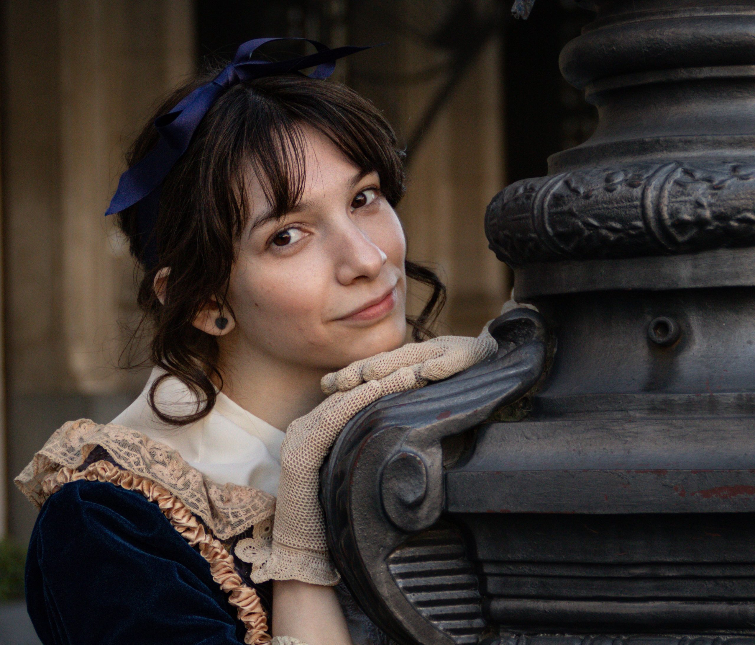A young woman in vintage attire posing beside an ornate structure in Buenos Aires.